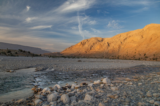 Aerial view of the rugged sun kissed mountains casting shadows over the rocky riverbed creating a stark contrast between light and shadow Pakistan. Aerial view of the rugged sun kissed mountains casting shadows over the rocky riverbed creating a stark contrast between light and shadow Pakistan.