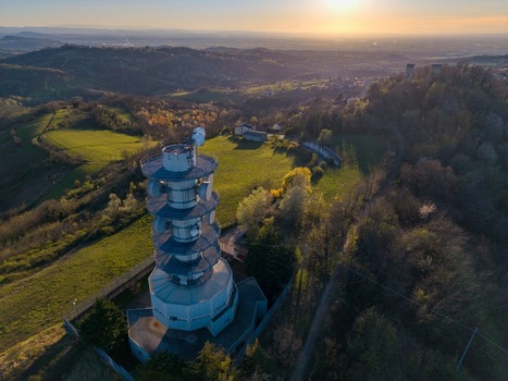 Aerial view of the Television Tower Tortona on a green hill surrounded by the rolling landscape of Piedmont at sunset Tortona Piedmont Italy.
