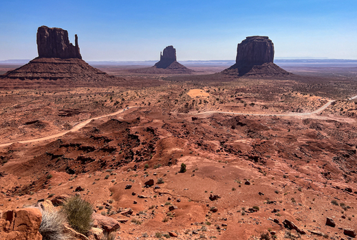 View of Monument Valley Tribal Park with iconic red sandstone buttes desert landscape and winding dirt roads under a clear blue sky in Oljato Monument Valley Utah United States.
