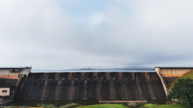 Aerial view of the massive concrete spillway of Midmar Dam with calm water and misty hills under an overcast sky in Howick KwaZulu Natal South Africa. Aerial view of the massive concrete spillway of Midmar Dam with calm water and misty hills under an overcast sky in Howick KwaZulu Natal South Africa.