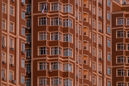 View of the modern brown facade of a residential apartment building featuring repetitive windows balconies and air conditioning units in Aktau Mangystau Region Kazakhstan.