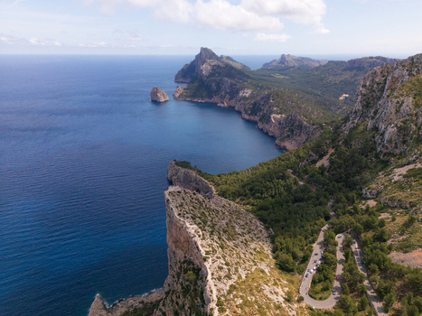 Aerial view of Cap de Formentor with steep limestone cliffs a winding mountain road and the deep blue Mediterranean Sea Balearic Islands Spain.