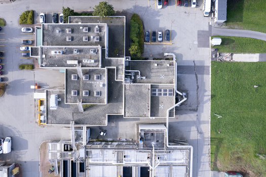 Aerial view of the Waste Water Treatment facility featuring industrial rooftops ventilation systems and surrounding parking areas in Richmond British Columbia Canada. Aerial view of the Waste Water Treatment facility featuring industrial rooftops ventilation systems and surrounding parking areas in Richmond British Columbia Canada.