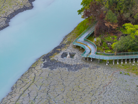 Aerial view of the Nine Frog Stack sculpture on the cracked dry bed of Sun Moon Lake with a wooden boardwalk and turquoise water in Yuchi Township Nantou County Taiwan. Aerial view of the Nine Frog Stack sculpture on the cracked dry bed of Sun Moon Lake with a wooden boardwalk and turquoise water in Yuchi Township Nantou County Taiwan.