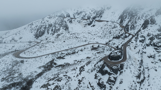 Aerial view of a winding mountain road snaking through the snow covered rocky slopes of the glacial valley in the Serra da Estrela Loriga Guarda District Portugal. Aerial view of a winding mountain road snaking through the snow covered rocky slopes of the glacial valley in the Serra da Estrela Loriga Guarda District Portugal.