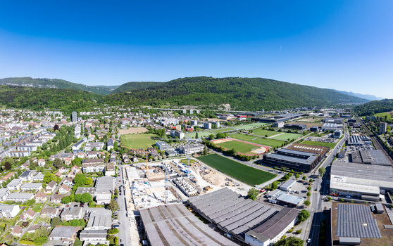 Aerial view of the Boezingenfeld Champ industrial area with construction sites sports fields and residential districts against green hills in Biel Bienne Canton of Bern Switzerland.
