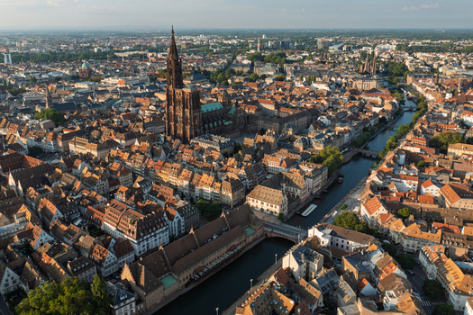 Aerial view of Cathedrale Notre Dame de Strasbourg surrounded by historic rooftops winding canals and dense urban architecture in Strasbourg Grand Est France.