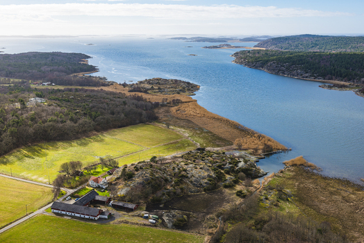 Aerial view of Nordre alv river flowing through rural landscape with farm buildings rocky terrain and fields in Vastra Gotaland County Sweden.