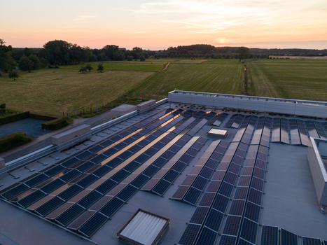Aerial view of solar panels on a flat roof with rural fields and sunset in the background in Zemst Flanders Belgium. Aerial view of solar panels on a flat roof with rural fields and sunset in the background in Zemst Flanders Belgium.