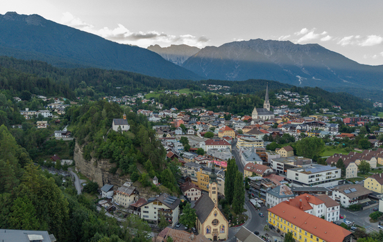 Aerial view of the town of Imst nestled in a mountain valley with traditional architecture church steeples and surrounding alpine peaks in Imst Tyrol Austria.