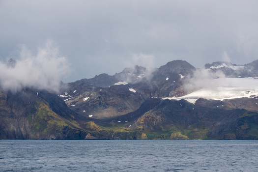 View of the rugged snow capped mountains and glaciers rising above the sea in South Georgia and the South Sandwich Islands.