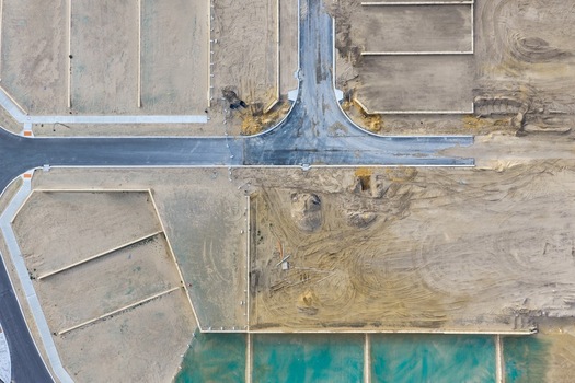 Aerial view of a residential development site under construction with newly paved roads marked plot boundaries and sandy soil in Perth Western Australia Australia. Aerial view of a residential development site under construction with newly paved roads marked plot boundaries and sandy soil in Perth Western Australia Australia.