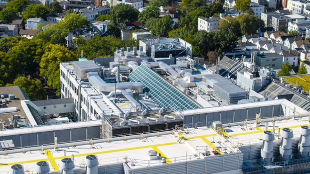 Aerial view of the industrial rooftop in Kendall Square featuring HVAC systems ventilation ducts and a glass skylight surrounded by houses in Cambridge Massachusetts United States. Aerial view of the industrial rooftop in Kendall Square featuring HVAC systems ventilation ducts and a glass skylight surrounded by houses in Cambridge Massachusetts United States.