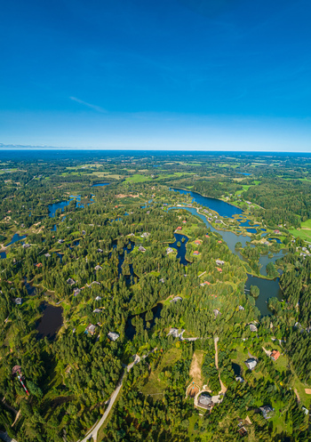 Aerial view of a lush forested landscape with numerous small lakes and winding waterways in Latvia. Aerial view of a lush forested landscape with numerous small lakes and winding waterways in Latvia.