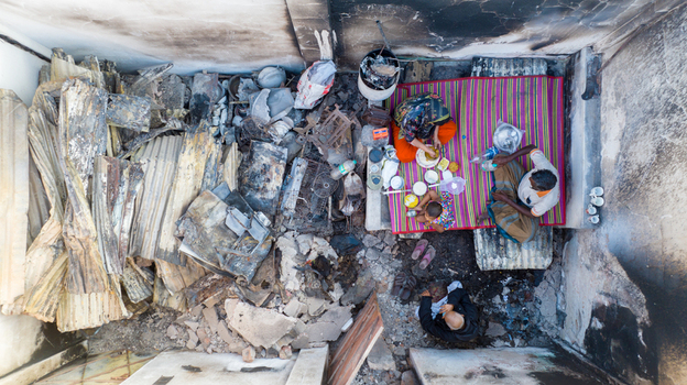 Aerial view of a family sitting on a mat amidst the charred remains of their home a stark contrast of life and devastation Dhaka Dhaka Division Bangladesh. Aerial view of a family sitting on a mat amidst the charred remains of their home a stark contrast of life and devastation Dhaka Dhaka Division Bangladesh.