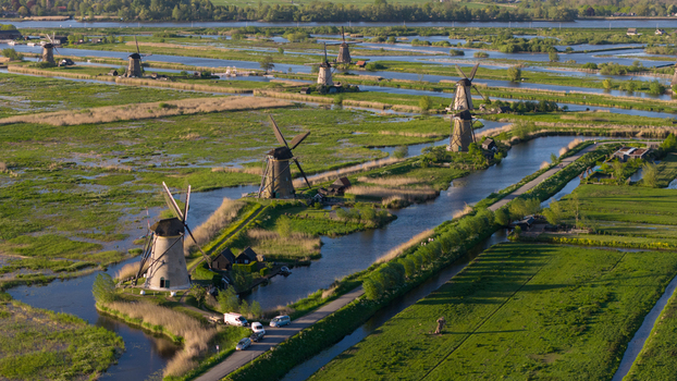 Aerial view of the historic Kinderdijk windmills standing along winding canals and lush green fields under soft sunlight Kinderdijk South Holland Netherlands. Aerial view of the historic Kinderdijk windmills standing along winding canals and lush green fields under soft sunlight Kinderdijk South Holland Netherlands.