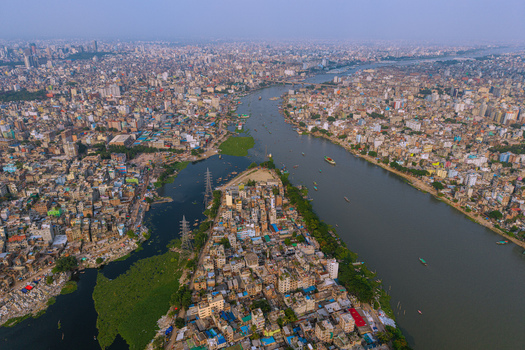 Aerial view of Buriganga River flowing through the dense urban landscape with numerous boats and crowded buildings Keraniganj Dhaka Division Bangladesh. Aerial view of Buriganga River flowing through the dense urban landscape with numerous boats and crowded buildings Keraniganj Dhaka Division Bangladesh.