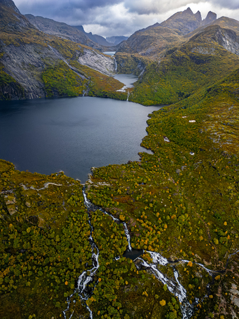 Aerial view of Stuvdalsvatnet lake surrounded by dramatic mountains cascading waterfalls and vibrant autumn foliage in Moskenes Nordland Norway. Aerial view of Stuvdalsvatnet lake surrounded by dramatic mountains cascading waterfalls and vibrant autumn foliage in Moskenes Nordland Norway.