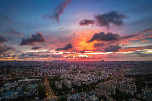 Aerial view of the Gusu district urban landscape at sunset with dramatic clouds over the city of Suzhou Jiangsu China.