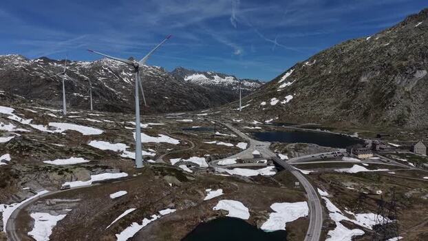 Aerial view of San Gottardo wind Park with wind turbines and winding roads in the Gotthard Pass under a blue sky in Airolo Ticino Switzerland.