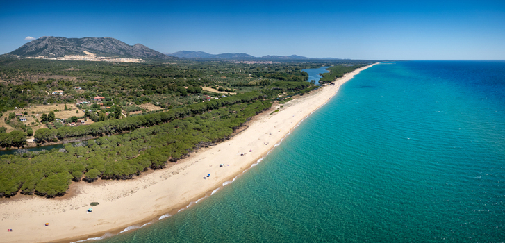 Aerial view of Spiaggia Osalla di Orosei with turquoise sea golden sand lush pine forest and distant mountains in Orosei Sardegna Italy. Aerial view of Spiaggia Osalla di Orosei with turquoise sea golden sand lush pine forest and distant mountains in Orosei Sardegna Italy.