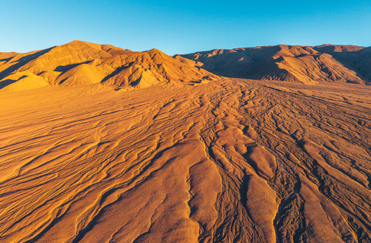 Aerial view of the arid Atacama Desert landscape with textured sand dunes and rugged mountains San Pedro de Atacama Antofagasta Chile. Aerial view of the arid Atacama Desert landscape with textured sand dunes and rugged mountains San Pedro de Atacama Antofagasta Chile.