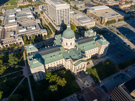 Aerial view of the Indiana Statehouse with its iconic green dome surrounded by urban buildings paved streets and green spaces in Indianapolis Indiana United States. Aerial view of the Indiana Statehouse with its iconic green dome surrounded by urban buildings paved streets and green spaces in Indianapolis Indiana United States.