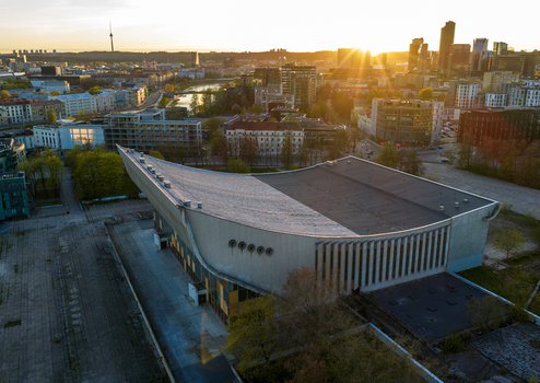 Aerial view of the brutalist Vilnius Palace of Concerts and Sports building at sunset with the city skyline and Neris River in the background Vilnius County Lithuania. Aerial view of the brutalist Vilnius Palace of Concerts and Sports building at sunset with the city skyline and Neris River in the background Vilnius County Lithuania.