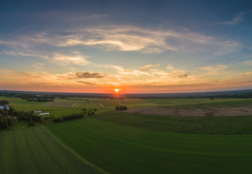 Aerial view of a vibrant sunset over the vast agricultural fields and rural landscape of Latvia. Aerial view of a vibrant sunset over the vast agricultural fields and rural landscape of Latvia.