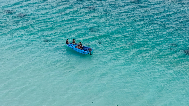 Aerial view of Motor boat featuring turquoise waters coral reefs wooden overwater bungalows and white sandy beaches in Pulau Derawan East Kalimantan Indonesia. Aerial view of Motor boat featuring turquoise waters coral reefs wooden overwater bungalows and white sandy beaches in Pulau Derawan East Kalimantan Indonesia.