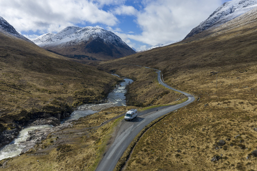 Aerial view of Glen Etive Waterfall View Point with a white campervan parked on a winding road through a rugged valley in Ballachulish Scotland United Kingdom.