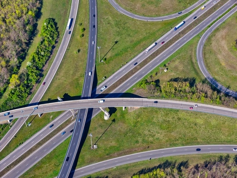 Aerial view of a highway interchange with vehicles flowing through the concrete and asphalt veins amidst green fields and trees Sausheim Grand Est France.