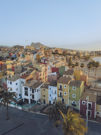 Aerial view of the colorful houses and sandy beach with palm trees in the coastal town of La Vila Joiosa Valencian Community Spain. Aerial view of the colorful houses and sandy beach with palm trees in the coastal town of La Vila Joiosa Valencian Community Spain.