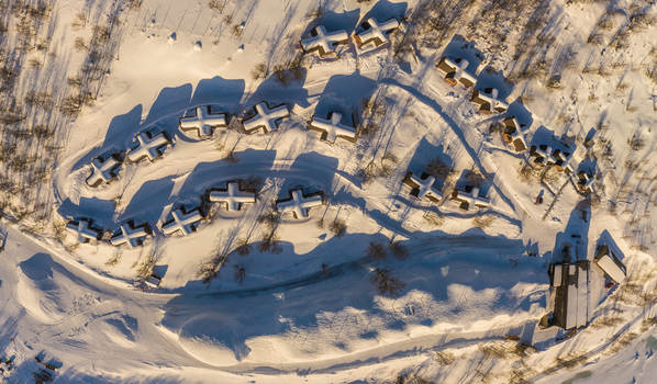 Aerial view of the snow covered cabins at the Snowhotel resort with deep snow and long shadows in the arctic landscape of Kirkenes Finnmark Norway. Aerial view of the snow covered cabins at the Snowhotel resort with deep snow and long shadows in the arctic landscape of Kirkenes Finnmark Norway.