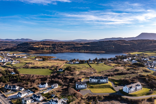 Aerial view of the village of Portnablagh with modern houses green fields and a lake set against rolling hills under a clear blue sky in Portnablagh County Donegal Ireland. Aerial view of the village of Portnablagh with modern houses green fields and a lake set against rolling hills under a clear blue sky in Portnablagh County Donegal Ireland.