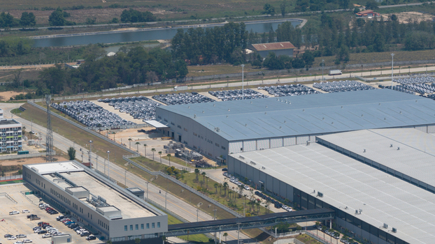 Aerial view of the BYD AUTO THAILAND CO. LTD. factory complex featuring large industrial buildings and parking lots filled with new vehicles in Phananikhom Rayong Thailand.