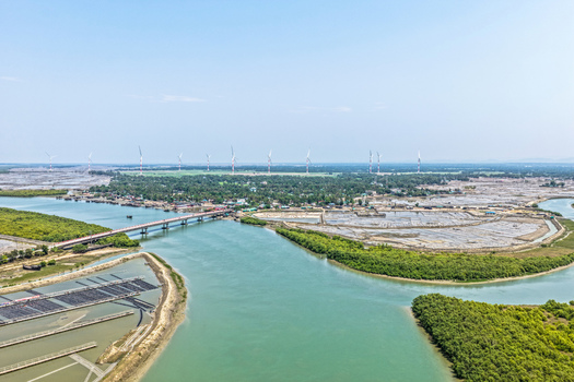 Aerial view of wind turbines standing tall against the horizon a bridge cutting across the turquoise water Cox s Bazar Chittagong Division Bangladesh. Aerial view of wind turbines standing tall against the horizon a bridge cutting across the turquoise water Cox s Bazar Chittagong Division Bangladesh.