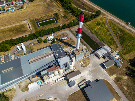 Aerial view of the Glas Trosch Alsace SAS industrial facility with a tall red and white chimney factory buildings and storage tanks near a canal in Hombourg Grand Est France.