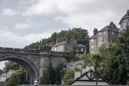 View of the historic Knaresborough railway viaduct rising above stone houses and lush greenery under a cloudy sky in Knaresborough England United Kingdom.