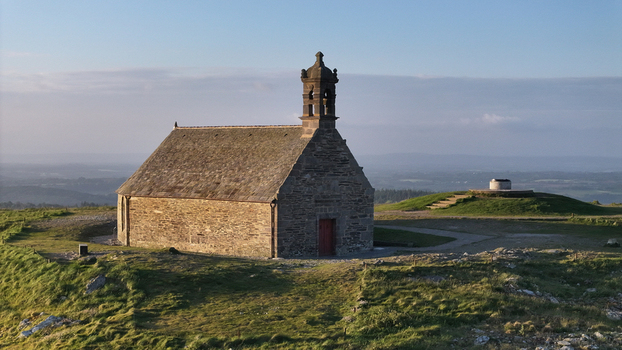 Aerial view of Chapelle Saint Michel de Brasparts on a grassy hilltop overlooking the rolling landscape of the Monts d Arree in Saint Rivoal Bretagne France. Aerial view of Chapelle Saint Michel de Brasparts on a grassy hilltop overlooking the rolling landscape of the Monts d Arree in Saint Rivoal Bretagne France.