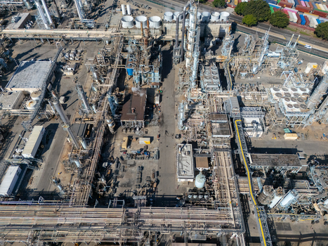 Aerial view of an industrial oil refinery complex featuring intricate piping networks tall distillation towers storage tanks and processing units in Carson California United States.