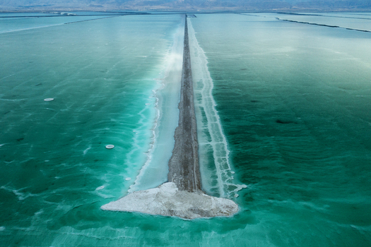 Aerial view of a road cutting through the blue green water leading to the serene horizon Ein Bokek South District Israel. Aerial view of a road cutting through the blue green water leading to the serene horizon Ein Bokek South District Israel.