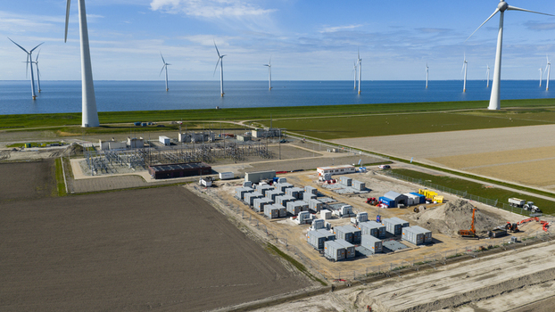 Espel Netherlands 04 April 2026 Aerial view of the Westermeerdijk wind farm and an electrical substation with battery storage containers near the coast under a blue sky.