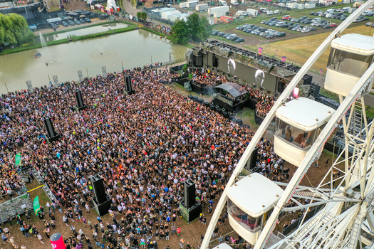 Herzogenaurach Germany 24 July 2025 Aerial view of the Open Beatz Festival with a large crowd gathered in front of the main stage a ferris wheel and a small pond.