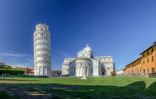View of the Leaning Tower of Pisa and the Cathedral of Pisa on the Piazza dei Miracoli with green lawns under a clear blue sky in Pisa Toscana Italy. View of the Leaning Tower of Pisa and the Cathedral of Pisa on the Piazza dei Miracoli with green lawns under a clear blue sky in Pisa Toscana Italy.