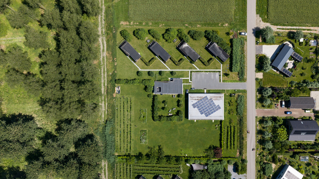 Aerial view of Ecodorp Bolderburen featuring sustainable residential buildings with solar panels lush green gardens and surrounding trees in Almere Flevoland Netherlands. Aerial view of Ecodorp Bolderburen featuring sustainable residential buildings with solar panels lush green gardens and surrounding trees in Almere Flevoland Netherlands.