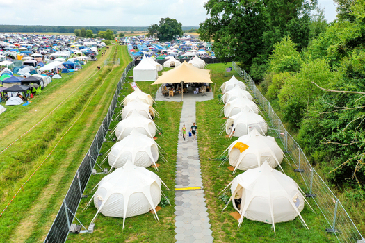 Herzogenaurach Germany 26 July 2025 Aerial view of the Open Beatz Festival glamping area with rows of white tents and a large tan canopy.