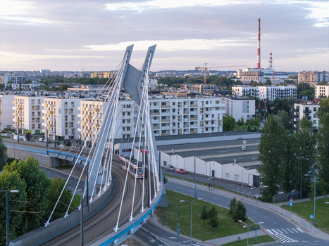 Aerial view of a modern cable stayed bridge with a tram crossing it surrounded by residential apartment buildings and industrial structures in Poland. Aerial view of a modern cable stayed bridge with a tram crossing it surrounded by residential apartment buildings and industrial structures in Poland.