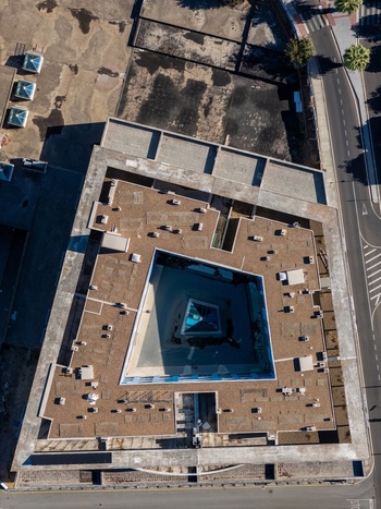 Aerial view of a modern building with a central courtyard and flat roof featuring numerous HVAC units situated near a road in Elvas Portalegre Portugal. Aerial view of a modern building with a central courtyard and flat roof featuring numerous HVAC units situated near a road in Elvas Portalegre Portugal.