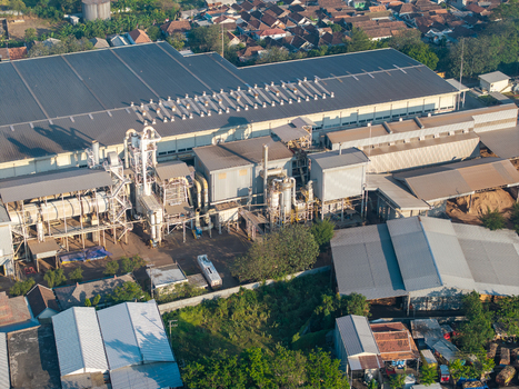 Probolinggo Indonesia 06 August 2026 Aerial view of an industrial factory complex with large metal rooftops processing machinery and surrounding residential buildings. Probolinggo Indonesia 06 August 2026 Aerial view of an industrial factory complex with large metal rooftops processing machinery and surrounding residential buildings.